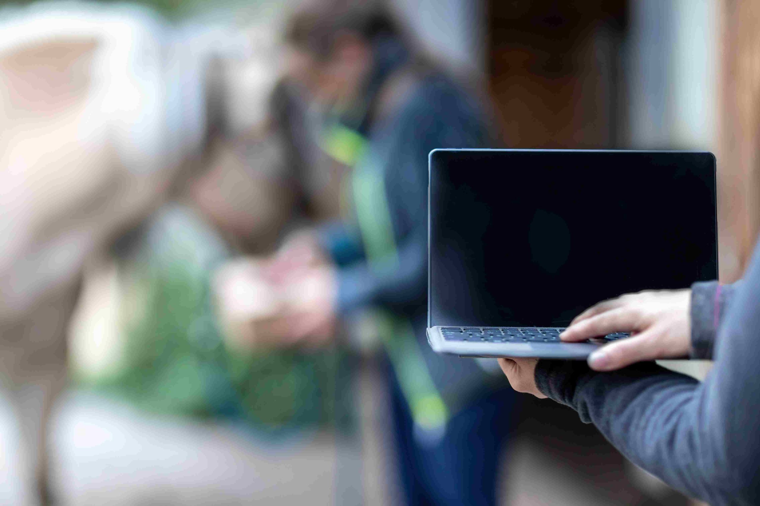 sur le forum populaire 1cheval, propriétaire de cheval utilisant un ordinateur pour consulter des conseils en ligne et acheter du matériel, avec un paddock et son cheval en arrière-plan flou