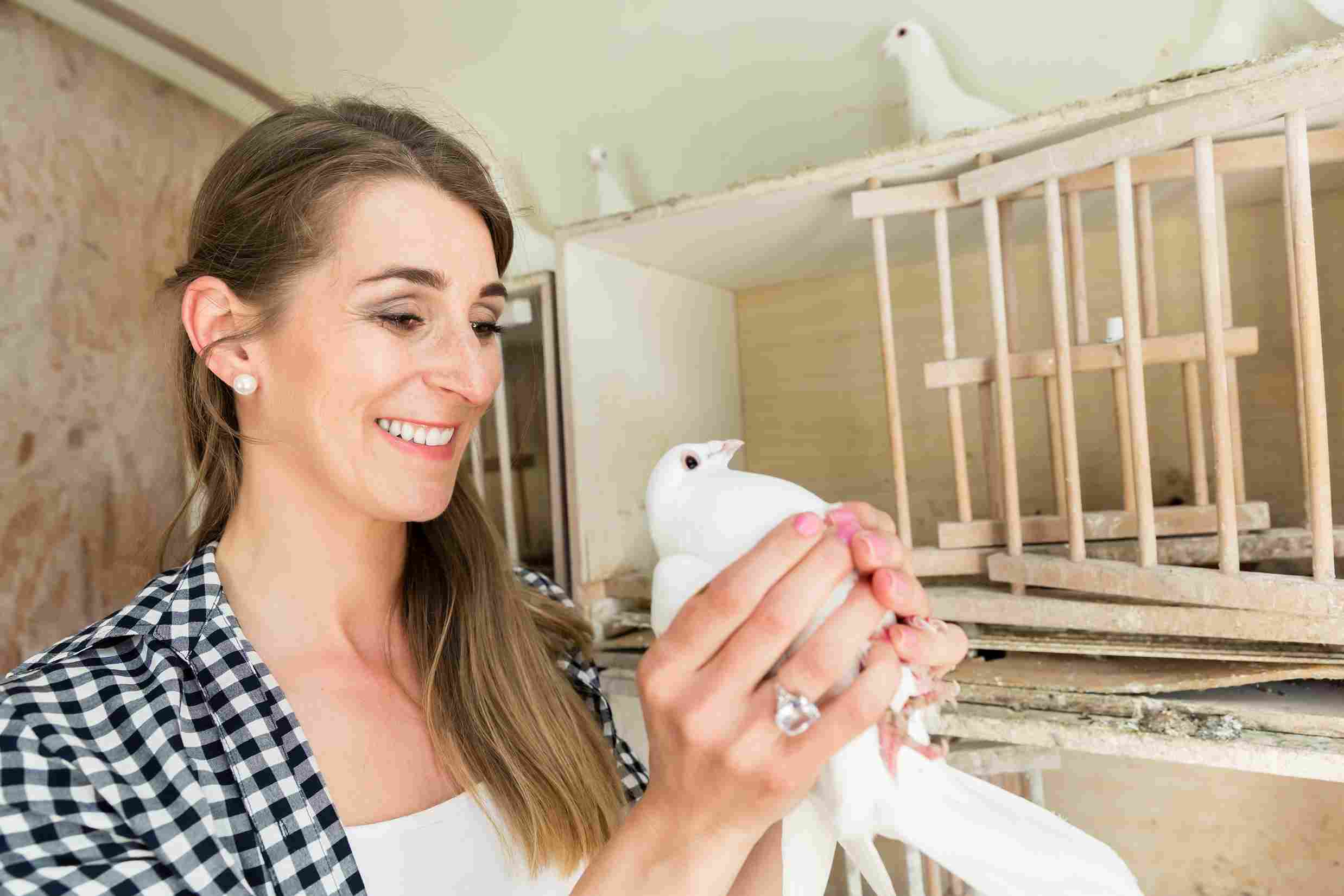 Femme colombophile tenant un pigeon voyageur dans un colombier traditionnel, illustration de la pratique colombophile du 02 dans l’Aisne