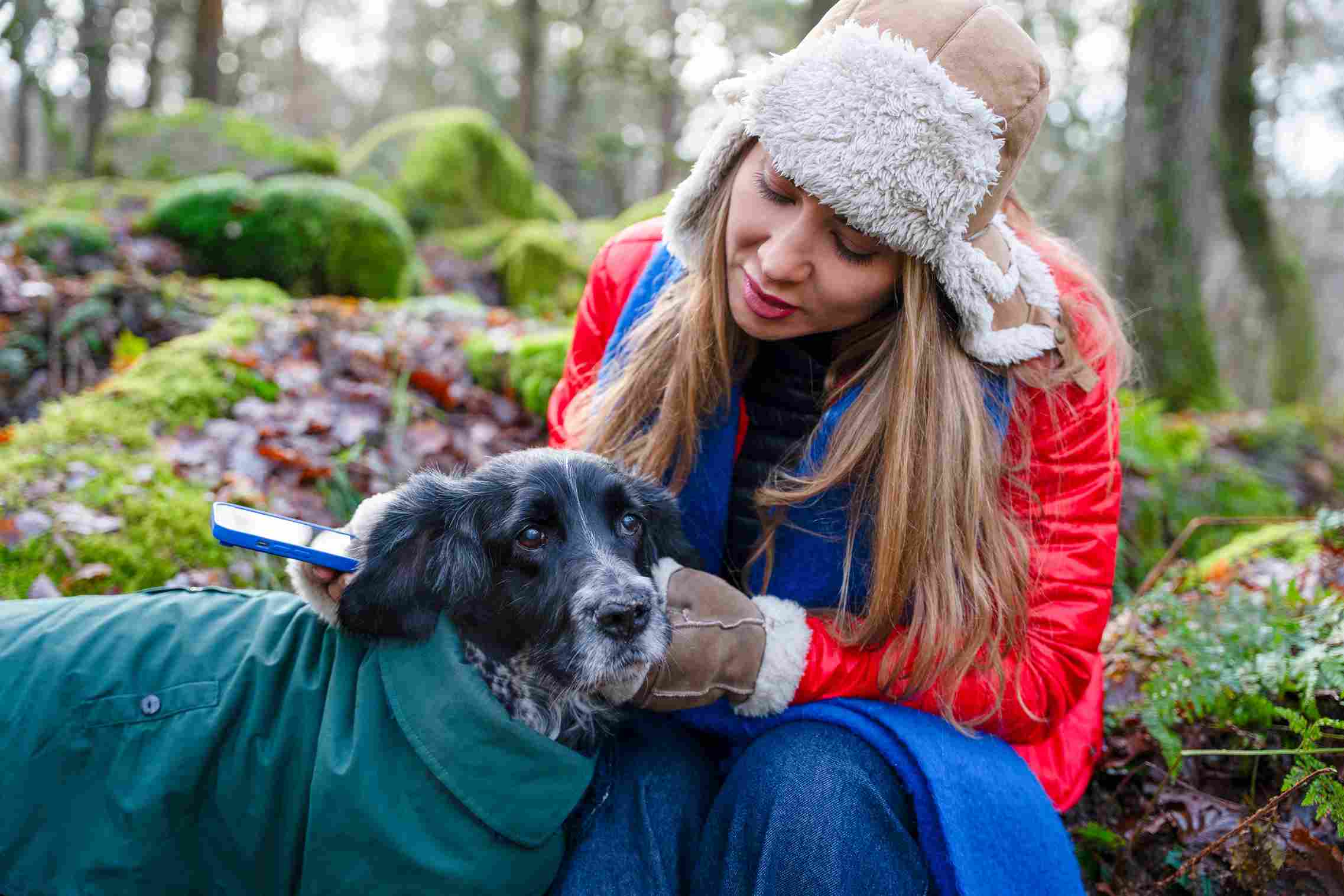 Quelle est la meilleure assurance pas trop cher pour chien: femme et son chien profitant d’un moment ensemble dans les bois lors d’une journée fraîche.
