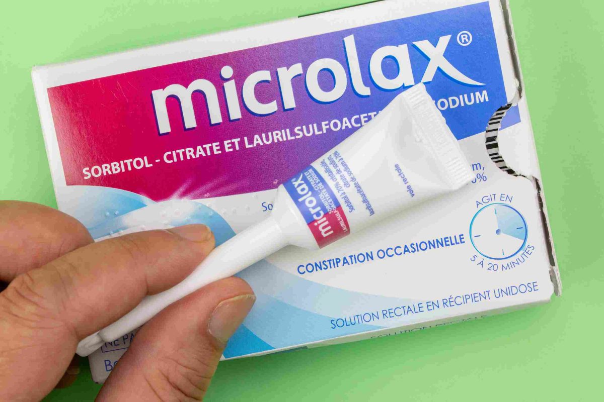 Microlax chat: gros plan sur une boîte de Microlax avec canule tenue en main pour traitement de la constipation chez le matou