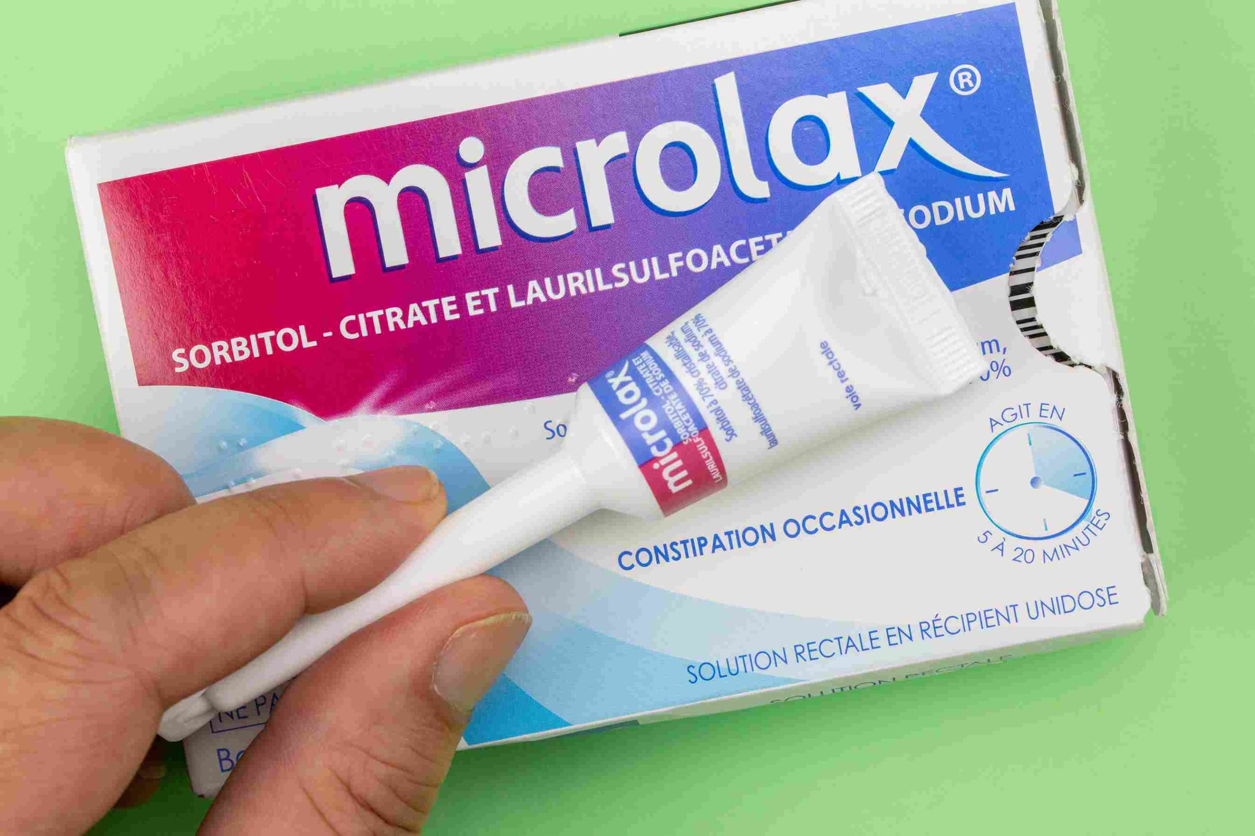 Microlax chat: gros plan sur une boîte de Microlax avec canule tenue en main pour traitement de la constipation chez le matou